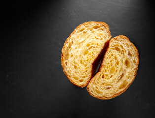 Doble Cross section of a croissant containing air on black background, top view