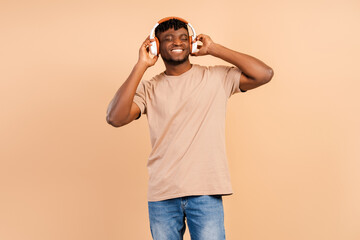 Happy, smiling african young hipster man wearing wireless headphones listening to music
