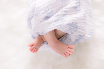 Newborn baby is wrapped in a blue blanket with his legs crossed. 