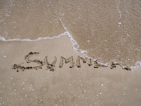 Concepto de "final de verano",una ola borra la palabra verano escrita en la arena