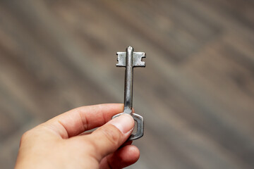 Person holding a small key made of nickel in their hand