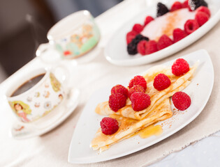 Preakfast of pancakes with fresh raspberries on table