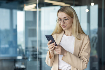 Smiling businesswoman using smartphone in modern office space
