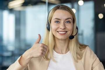 Smiling customer service representative with thumbs up, wearing a headset in a modern office setting