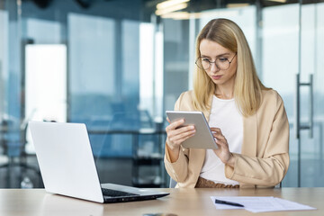 Focused businesswoman working on tablet in modern office, analyzing data
