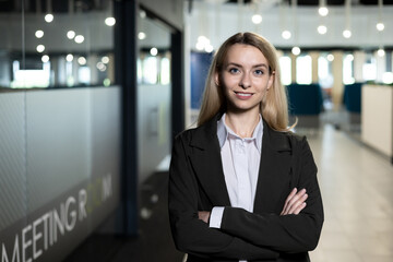 Confident businesswoman standing in a modern office space with arms crossed