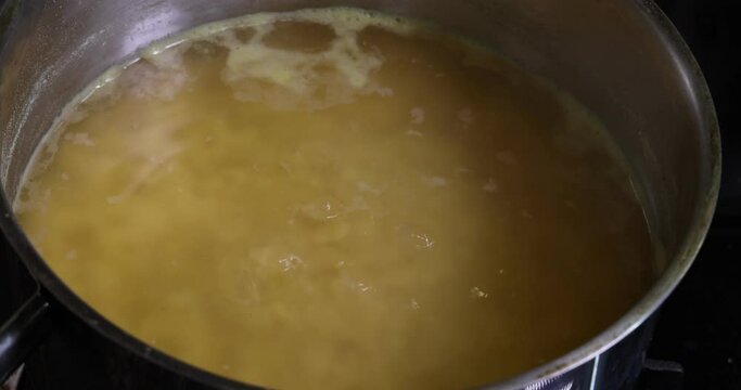 Boling cooking red lentil dal in pot of water bubbling moving 