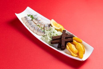 Herring, potato wedges and croutons in a plate.