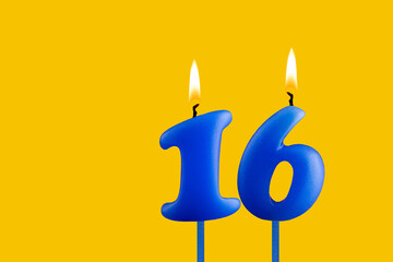 Blue birthday candle on yellow background - Number 16