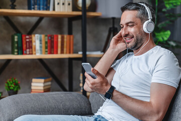 Happy caucasian man listening music song podcast watching video movie have zoom call on mobile...