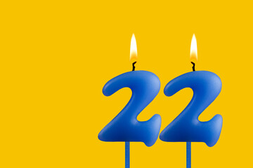 Blue birthday candle on yellow background - Number 22