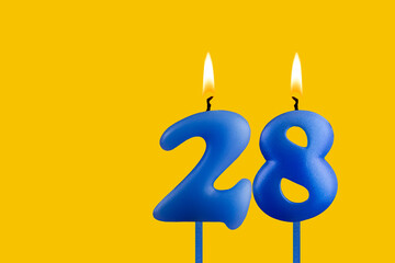 Blue birthday candle on yellow background - Number 28