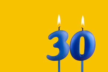 Blue birthday candle on yellow background - Number 30