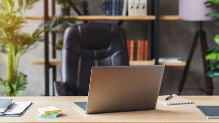 Close-up of open laptop on wooden table. Nearby is a tablet computer, a smartphone, paper graphics,...