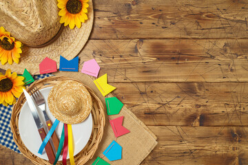Festa Junina party table setting with traditional decorations on wooden background. Brazilian summer harvest festival concept. Top view, flat lay
