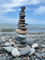 Beautiful pyramid of pebbles on the seashore with splashing waves on a sunny day