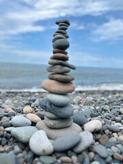 Beautiful pyramid of pebbles on the seashore with splashing waves on a sunny day