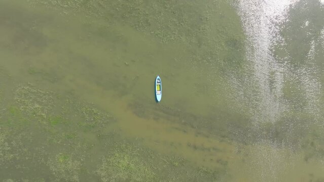 A drone is descending to a rowboat vertically at a high speed from a far distance in Manyas lake.