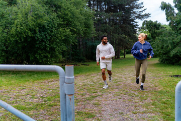 Friends jogging through a park, smiling and enjoying their run. They are dressed in sportswear, highlighting an active and healthy lifestyle.