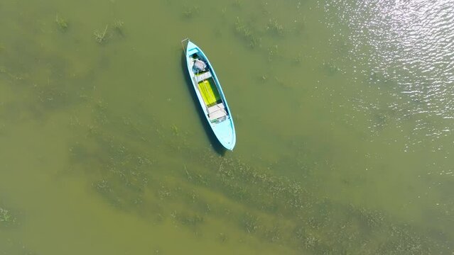 A drone and a rowboat in Manyas lake. A drone is rising up above a green lake focusing on the blue yellow boat
