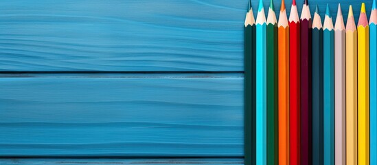 A copy space image featuring a variety of vibrant pencils placed on a background of blue wooden surface - Powered by Adobe