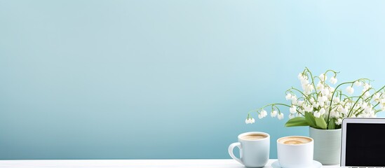 A work from home setup with a desk laptop coffee and a lovely bouquet of lily of the valley flowers The background is a calming blue creating a serene atmosphere Perfect for bloggers freelancers and