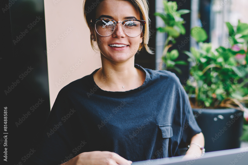 Poster portrait of cheerful female student looking in camera during searching new interesting websites via 