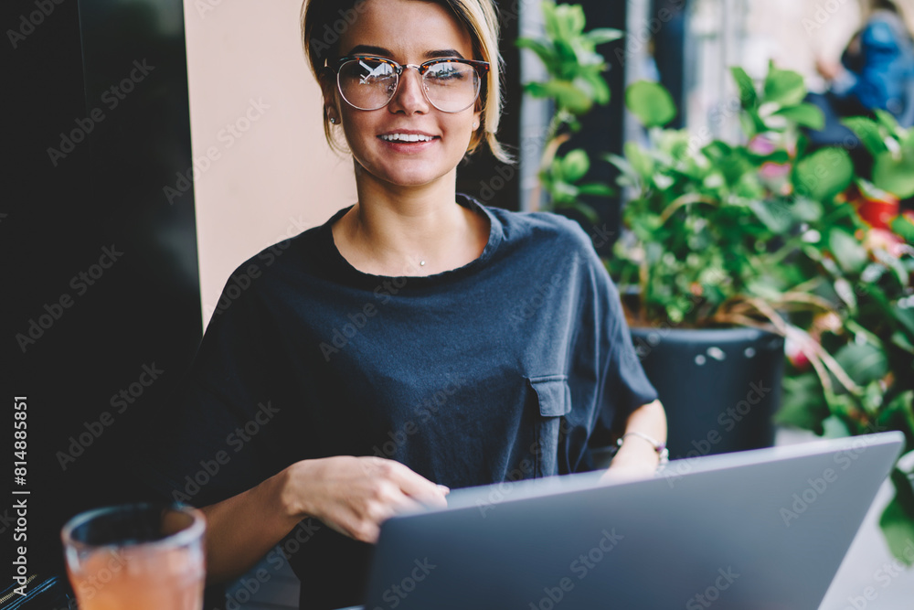 Poster portrait of cheerful female student looking in camera during searching new interesting websites via 