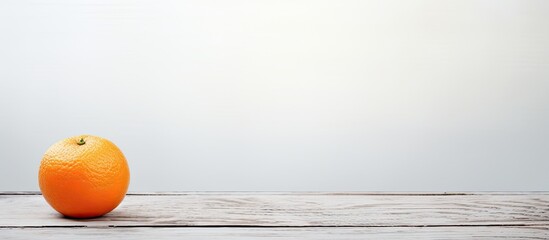 A lonely orange sitting on a textured white wood plank background creating a captivating image with...