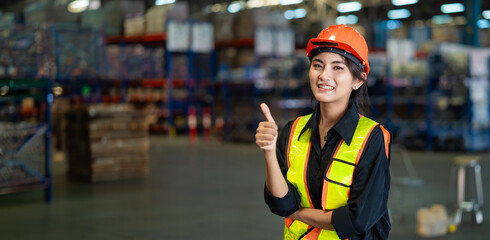 A woman wearing a safety vest and a hard hat is giving a thumbs up. She is smiling and she is happy