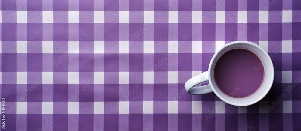 Poster top view of an empty mug cup placed on a fabric background with a purple check pattern creating a co