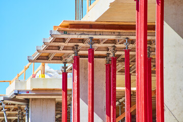 Vibrant Red Scaffolding and Wood Beams at Construction Site, Eye-Level View
