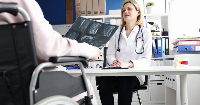 Radiologist examines a woman in wheelchair and x-rays spine. Spinal injury and medical care concept