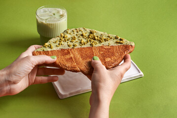 flat croissant in woman hands and glass of matcha with ice