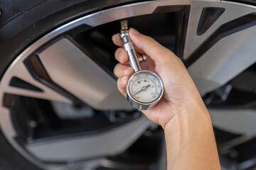 The woman is checking the tire pressure of her car before heading out for a trip.