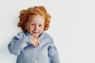 Happy little girl with red hair in blue sweater smiling at camera, beauty of childhood captured in photo