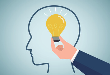 Inspiration concept.Hand holding luminous light bulb, putting in human brain.