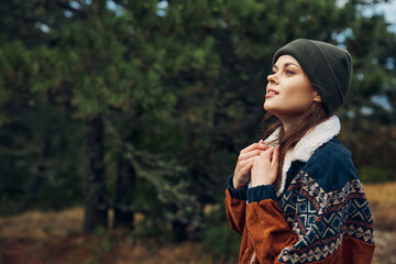 A young woman in a cozy sweater and beanie standing amidst the serene beauty of a forest getaway