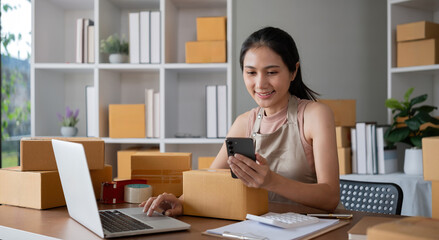 Smiling young woman in warehouse scanning package with smartphone