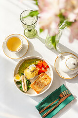 Light breakfast in a restaurant with green tea, toast, egg, avocado and salmon
