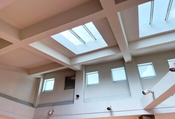 Indoor roof ceiling in huge building area with square windows and wall lamps isolated on horizontal...