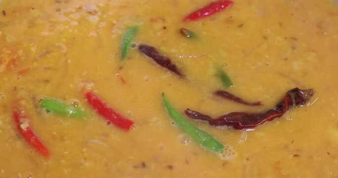 Adding boiling dal lentil into bagar tadka with deep fry tomato onion garlic cumin red dry chilli spice stair cooking dal ghotni whisk 
