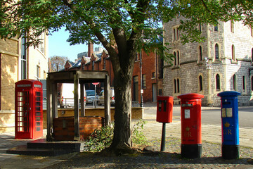 traditional British post boxes with royal ciphers and a red outdoor telephone box under a tree, Windsor Castle in the distance, UK