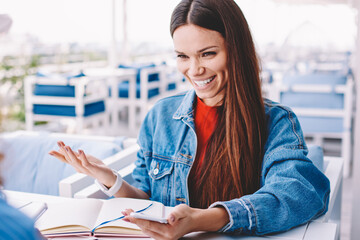 Back view of cheerful hipster girl holding smartphone gadget and discussing funny joke from social...