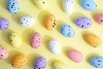Easter eggs on light yellow top view, pattern of Easter eggs
