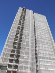 tall skyscraper with the scaffolding for the installation of thermal insulating panels to protect...