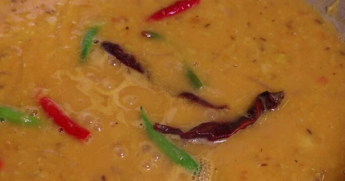 Adding boiling dal lentil into bagar tadka with deep fry tomato onion garlic cumin red dry chilli spice stair cooking dal ghotni whisk 