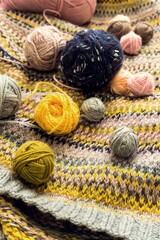 Multi-colored balls of knitting yarn on a hand-knitted jacquard background. Soft focus, shallow depth of field, blur, retro stylization.