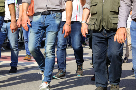Legs of men walking down the street in jeans during a parate  with faces unseen