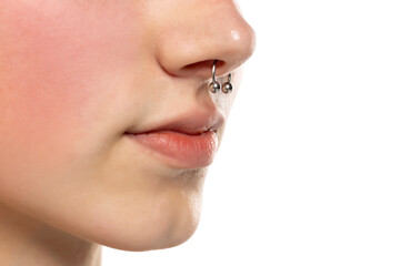 Closeup of a young serious woman's visage with piercing septum hanging from her nose